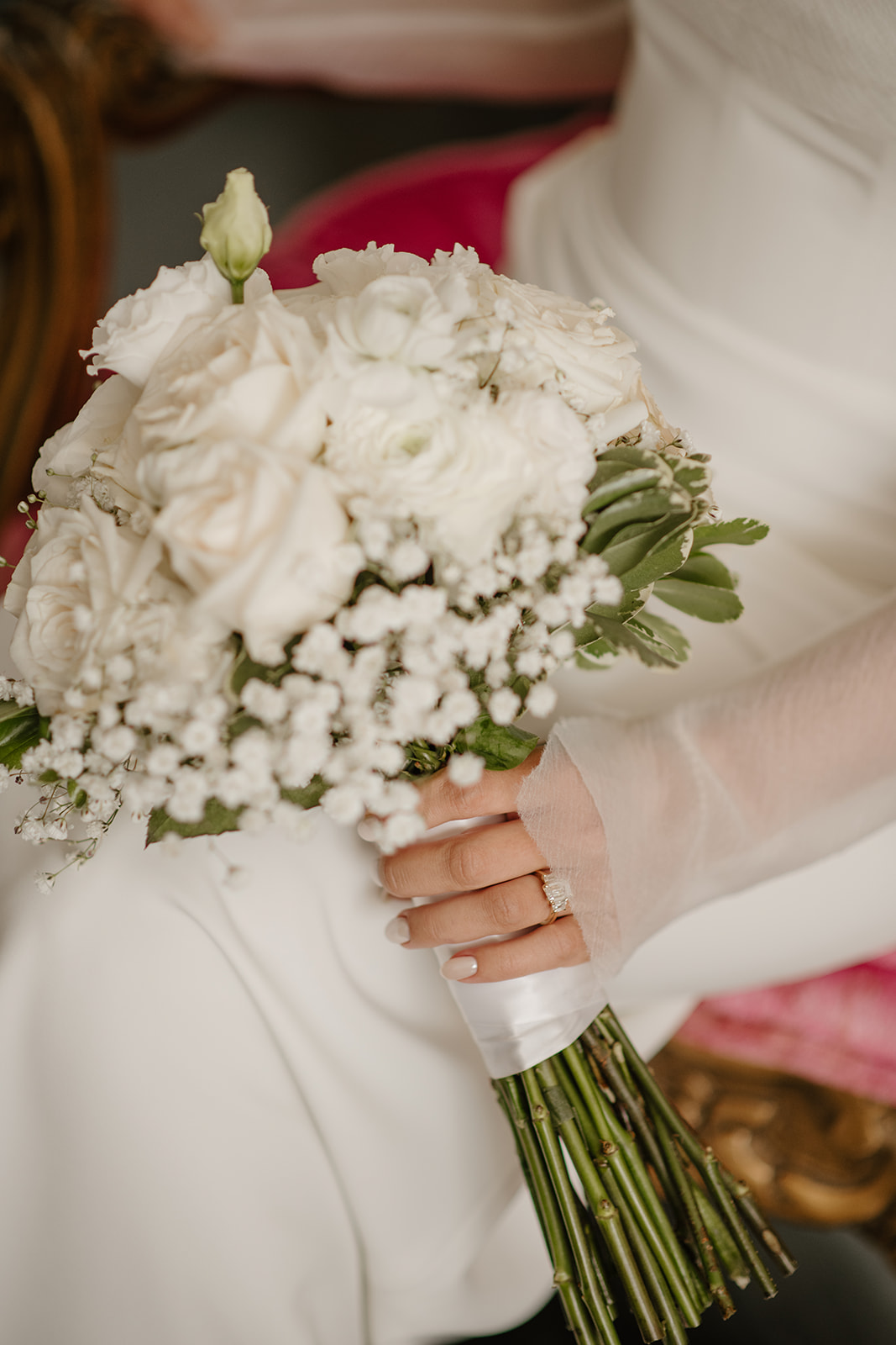 Close-up of the bride holding a white rose bouquet, showing her sheer gloves and engagement ring.